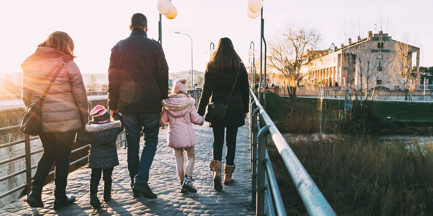 Father walking down the street with his two families on a sunny winter's afternoon. Atypical family concept